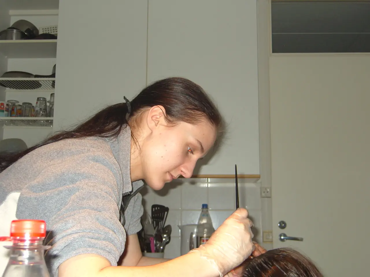 In this image there is a woman sitting and applying a cream on another person 's hair ,and at the...