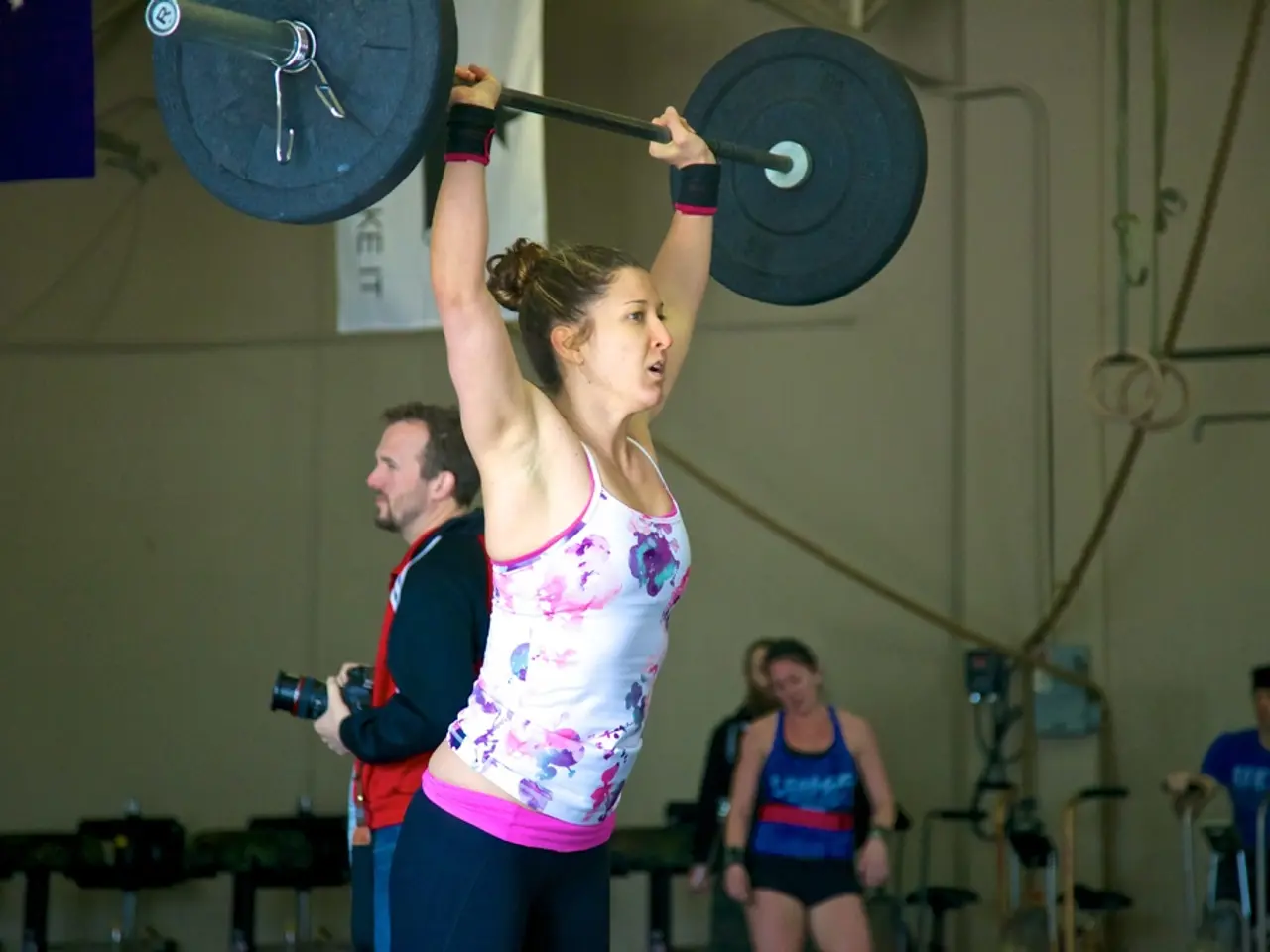In the foreground of the picture there is a man lifting weights. In the background there are people...