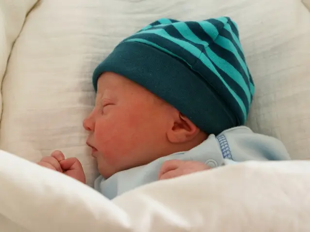 In this image we can see a baby sleeping. At the bottom there is a blanket.