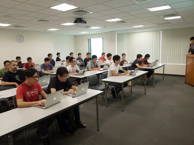 In this image there are group of people sitting and working on a laptop,the man standing here and...
