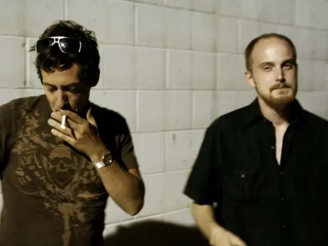 In the image there is a man in black shirt standing on the right side and another man in t-shirt...