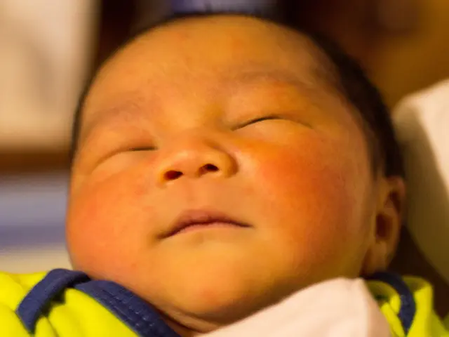 In the foreground of this image, there is a baby in green dress and the background image is blur.