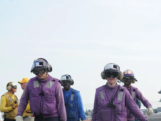 Here is a person lying on the stretcher. I can see four people carrying this stretcher. There are...